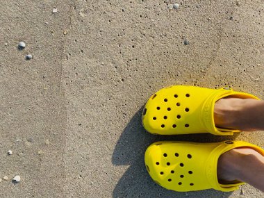 Bright yellow Rubber Crocs. Summer vacation trendy second-hand shoes from the top. Stylish sandals. Sustainable fashion footwear, reusable material
