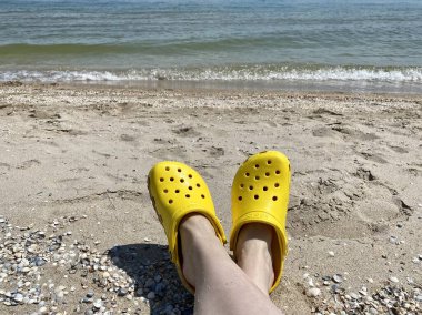 Bright yellow Rubber sandals or Crocs. Summer vacation trendy shoes. Stylish sandals. Yellow footwear.