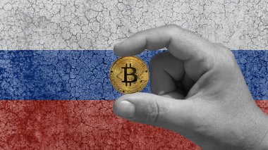 Bir elinde Bitcoin, btc, geleceğin kripto para birimi. Arka planda, harap olmuş beton duvardaki Rus bayrağı.