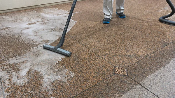 赤御影石の床からプロの掃除機と残留汚れた水の除去 — ストック写真