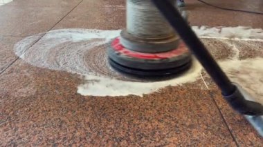 Profesyonel bir zemin temizleyicisiyle kırmızı granit zemini yıkamak ve profesyonel bir elektrikli süpürgeyle siyah suyu temizlemek.