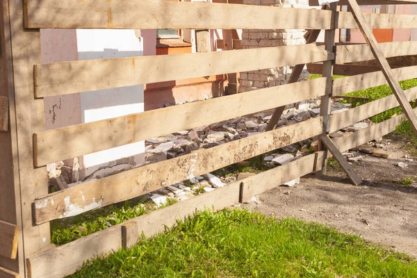 Ξύλινο φράχτη με τρύπες περικλείει το σπίτι, το οποίο είναι επισκευές — Φωτογραφία Αρχείου