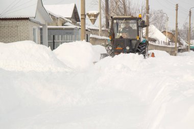 Kışın küçük bir traktör caddeyi temizler, çok kar yağar. 14 Şubat 2021, Rusya, 242600. Bryansk bölgesi