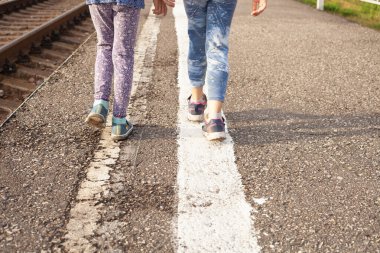 Çocuklar demiryolu kenarındaki şerit boyunca yürüyorlar.