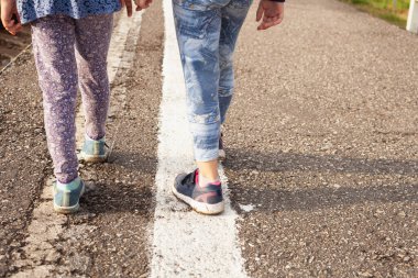 Yazın beyaz şeritte yürüyen iki kız..