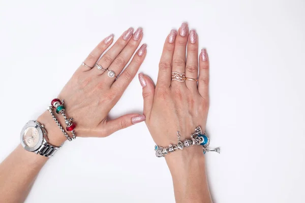 Damskie dłonie z manicure leżą na białym tle. na dłoniach pierścienie, bransoletki — Zdjęcie stockowe