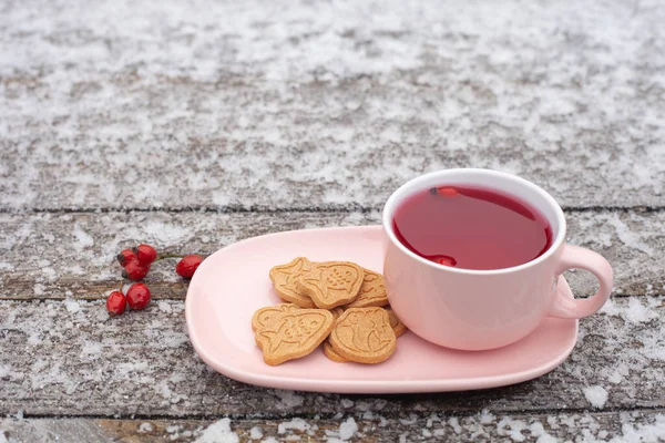 A pink mug of rosehip tea stands on a wooden surface in winter. frost is visible — Stock Photo, Image