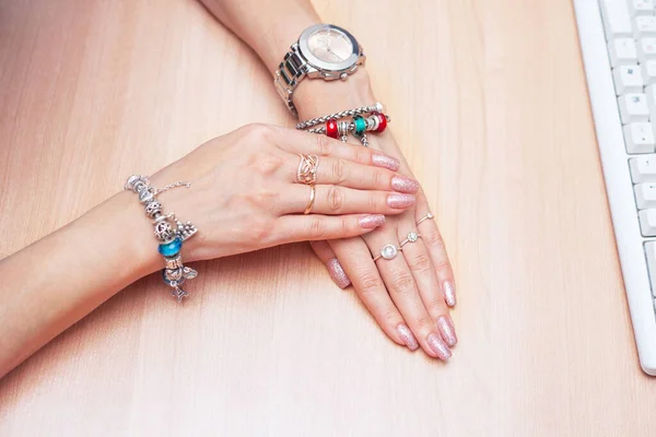 Piękne ręce kobiet z biżuterią i manicure na stole w pobliżu klawiatury — Zdjęcie stockowe