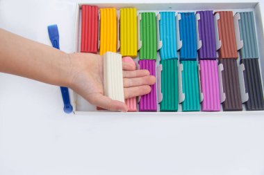 Çocuğun elinde beyaz bir platsilin parçası var. çok renkli plastiklerle kutunun altında..