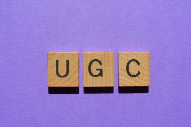 UGC, mor arkaplanda izole edilmiş ahşap alfabe harfleriyle oluşturulan Kullanıcı İçeriği kısaltması