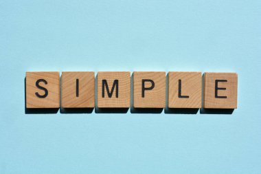 Basit, düz mavi arkaplanda izole edilmiş tahta alfabe harfleriyle kelime.