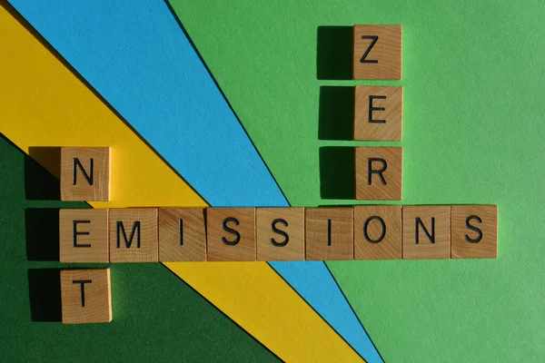 Net Zero Emissions, words in wooden alphabet letters in crossword form isolated on blue green and yellow background