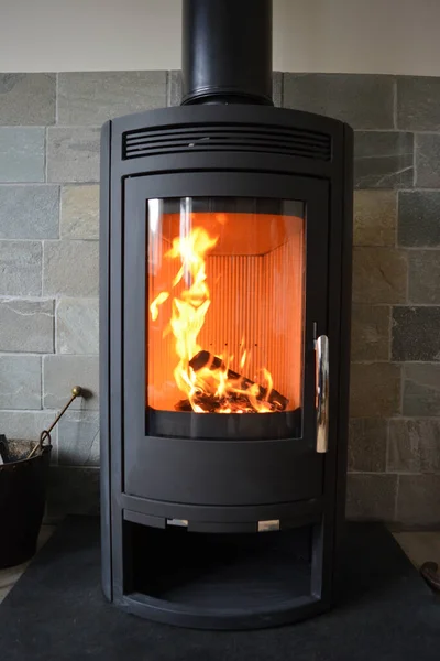 Fire lit in new wood burning stove set on slate floor with tiles behind.
