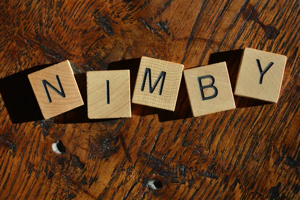 NIMBY, acronym for Not in My Back Yard, in wooden alphabet letters isolated on background