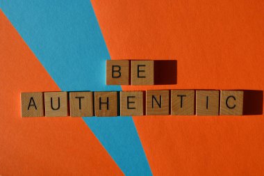 Otantik ol, ahşap alfabe harflerindeki kelimeler turuncu ve mavi arka planda izole edilmiş.