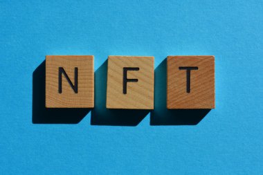 NFT, geri ödemesiz jetonun kısaltması, mavi arkaplanda tahta alfabe harfleriyle.