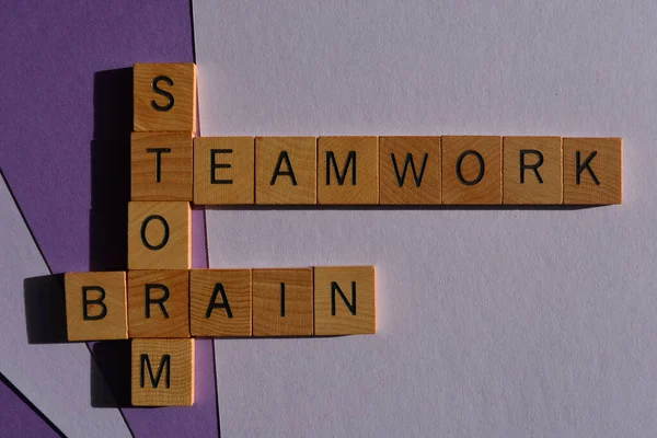 Teamwork, brain storm, words in wooden alphabet letters in crossword form isolated on purple background