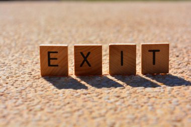 Çıkış, ahşap alfabe harflerindeki sözcük arka planda ışıklandırılmış ve izole edilmiş.