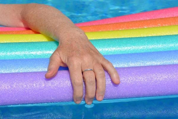 Γυναικείο Χέρι Ακουμπισμένο Πολύχρωμα Νούντλς Που Επιπλέουν Στην Πισίνα — Φωτογραφία Αρχείου