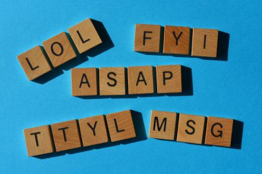 LOL, FYI, ASAP, TTYL, MSG, kısaltmalarda kullanılan kısaltmalar mavi arkaplanda izole edilmiş tahta alfabe harfleri.
