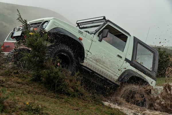 Off road car full of mud splashing water out of a lake