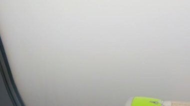 Uçak penceresinden zaman ayarlı. Uçak yoğun gri bulutlardan havaalanına iner. Uçağın türbini yeşil..