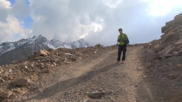 Человек с дистанционным управлением наблюдает за приземлением беспилотника на дорожных горах Эльбруса — стоковое видео