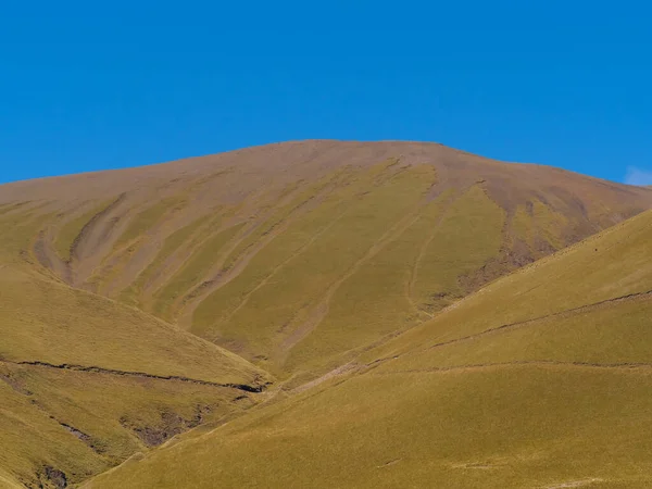 Naturalne tło, krajobraz - ogromne zielone wzgórze i jasne błękitne niebo — Zdjęcie stockowe