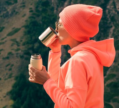 Yürüyüşten sonra kupadan içen kadın, açık hava aktivitesi.