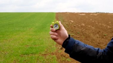 Bahar ekimi zamanı. Çiftçilik ve tarım kavramı. Ekme zamanı. Tarla yeşil, saban sürmüş ve yeşil alarmlı bir adamın eli var. Saha işi sezonu.