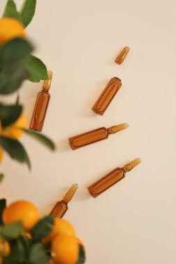 C vitamini mezoterapi serumu. C vitamini ampulleri ve bej arka planda mandalina meyveleri. Ampuller ve C vitamini organik kozmetik serumu. Sağlık ve güzellik. 