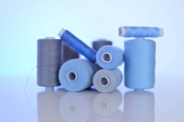 Set di fili per cucire. Bobine di filo blu e grigio su sfondo blu. Concetto di cucito e cucito. Hobby e artigianato — Foto Stock