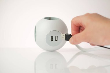 USB adaptörü. USB bağlantısı olan bir soket. Şarj istasyonu. Şarj aletindeki USB kablosu da dahil. Kare beyaz soket ve telefon şarjlı kadın elleri. .gadget ve teknoloji.