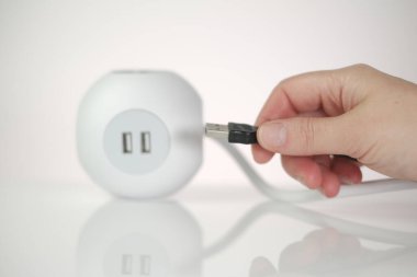 USB adaptörü. USB bağlantısı olan bir soket. Şarj istasyonu. Şarj aletlerindeki USB kablosunu ve teknolojiyi de ekleyin. Kare soket ve telefon şarjlı kadın elleri..