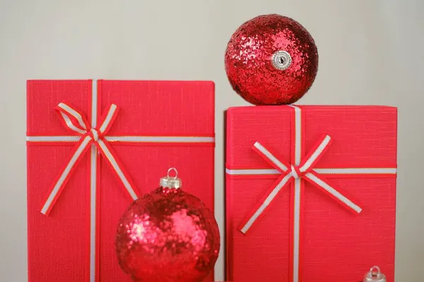 Gifts for the winter holidays. Cristmas presents. Red boxes and red Christmas balls on a light beige background. Festive christmas background in red beige colors — Stock Photo, Image