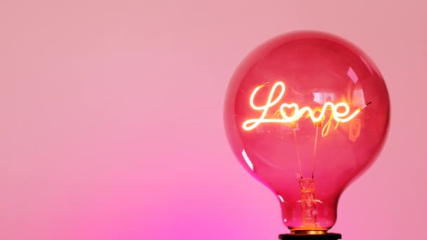 Valentines Day.Light bulb with the inscription love on a pink background — Stock Video