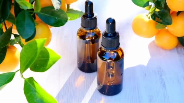 Мандаринська олія. Citrus subsitive oil.organic natural bio oil Мандаринська олія в коричневих скляних пляшках і кущах мандарина в сонячному літньому саду. — стокове відео