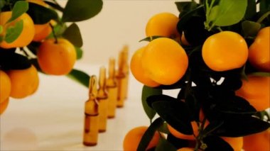 Vitamin C. Cam ampuller ve bej arka planda mandalina meyveleri. Organik doğal kozmetik.