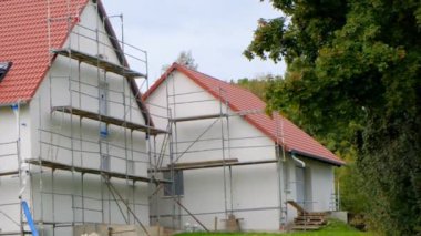 İskelede kırmızı çatısı olan yeni bir ev. Ev inşaatı. İnşaat malzemeleri ve yeni bir ev inşa etme süreci.