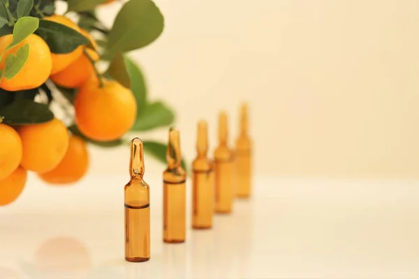 Sérum de vitamine C. Ampoules en verre et buissons de mandarine. Ampoules et sérum de vitamine C. Santé et Beauté. Cosmétiques naturels biologiques. — Photo