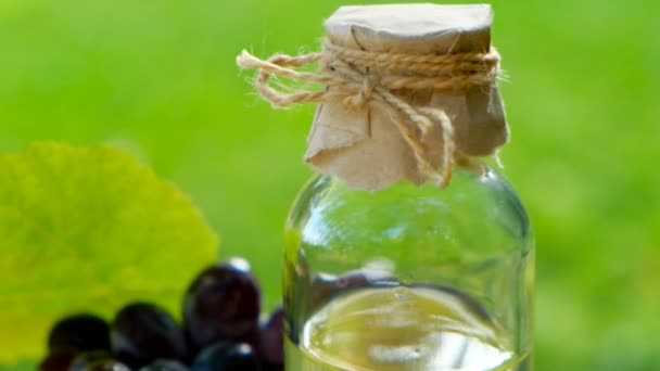 Druvkärneolja, vinäger. Glasflaska och en massa mörka druvor .Organic Natural Grape Seed Oil — Stockvideo
