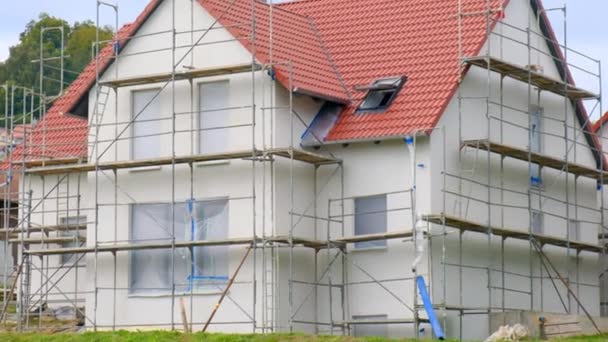 Ev inşaatı. İskelede kırmızı çatısı olan yeni bir ev. İnşaat malzemeleri ve yeni bir ev inşa etme süreci. — Stok video