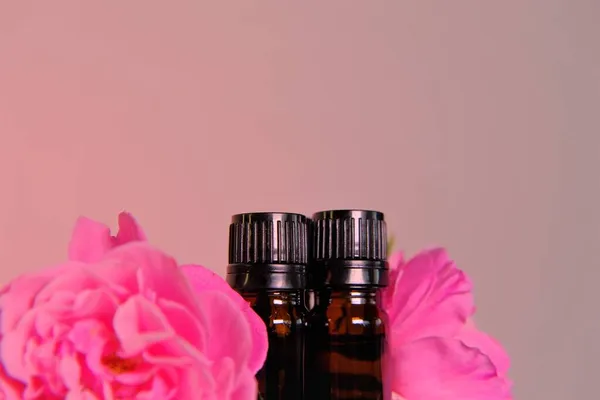 Aceite esencial de rosa.Concepto de aromaterapia y cosmética. Conjunto de botellas de vidrio marrón y flores de rosa rosa sobre aceite de rosa background.natural rosa. — Foto de Stock