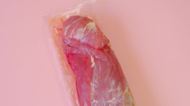 Carne de cerdo. Carne envasada al vacío sobre un fondo rosado.Productos cárnicos. textura de carne. — Vídeos de Stock