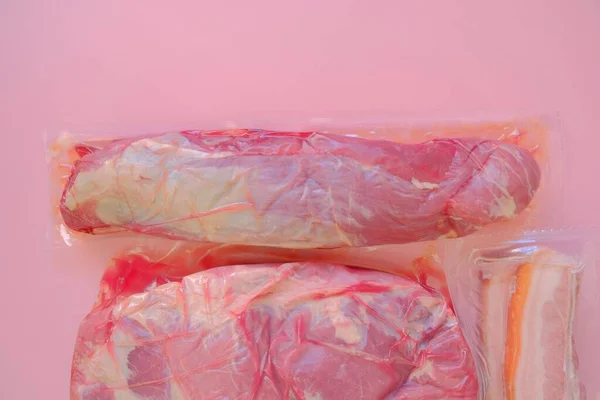Χοιρινό κρέας. Φρέσκα κομμάτια χοιρινού. Τροφές πρωτεϊνών.Κενό συσκευασμένο κρέας σε ροζ φόντο.Προϊόντα κρέατος. — Φωτογραφία Αρχείου