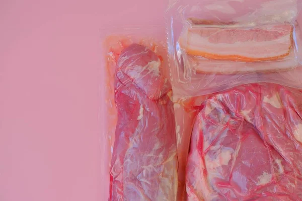 Carne de porco. Pedaços de porco frescos. Alimentos proteicos. Textura da carne.Carne embalada a vácuo sobre fundo rosado.Produtos à base de carne. — Fotografia de Stock