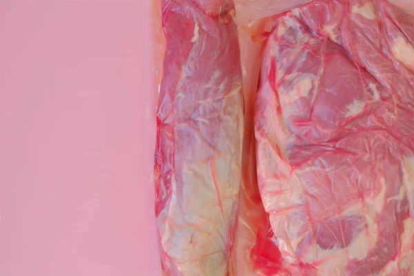 Schweinefleisch.Frische Schweinefleischstücke. Proteinnahrung. Fleisch Textur.Vakuumverpacktes Fleisch auf rosa Hintergrund. — Stockfoto