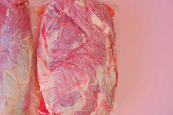 Schweinefleisch.Frische Schweinefleischstücke. Fleisch Texture.Vakuumverpacktes Fleisch auf rosa Hintergrund .Fleischprodukte. — Stockfoto