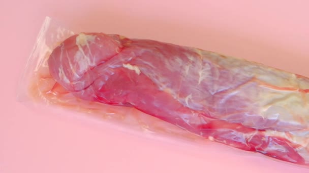 Carne de cerdo. Carne envasada al vacío sobre un fondo rosado.Productos cárnicos. textura de carne. — Vídeos de Stock