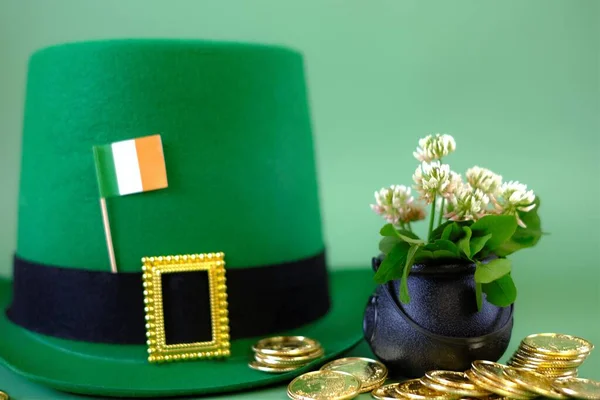 Il giorno di San Patrizio. cappello leprecauno, bandiera d'Irlanda, bombetta con monete d'oro, mazzo di trifogli su sfondo verde. Festa di San Patrizio. St patricks giorno sfondo — Foto Stock